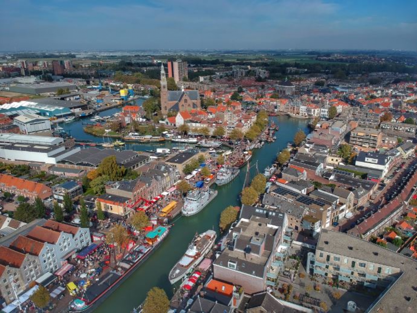 luchtfoto van stad met huizen, industrie, kerk, haven en kanaal