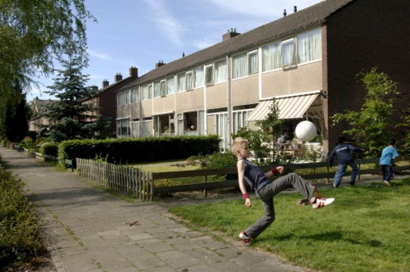 foto van spelend kind met bal op veldje in een woonwijk