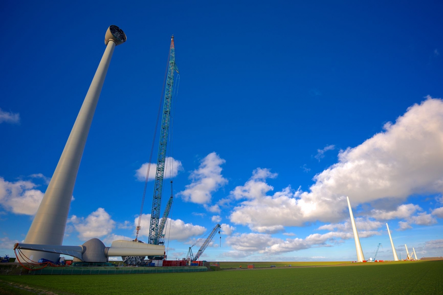 foto van de aanbouw van windmolens in een weids landschap
