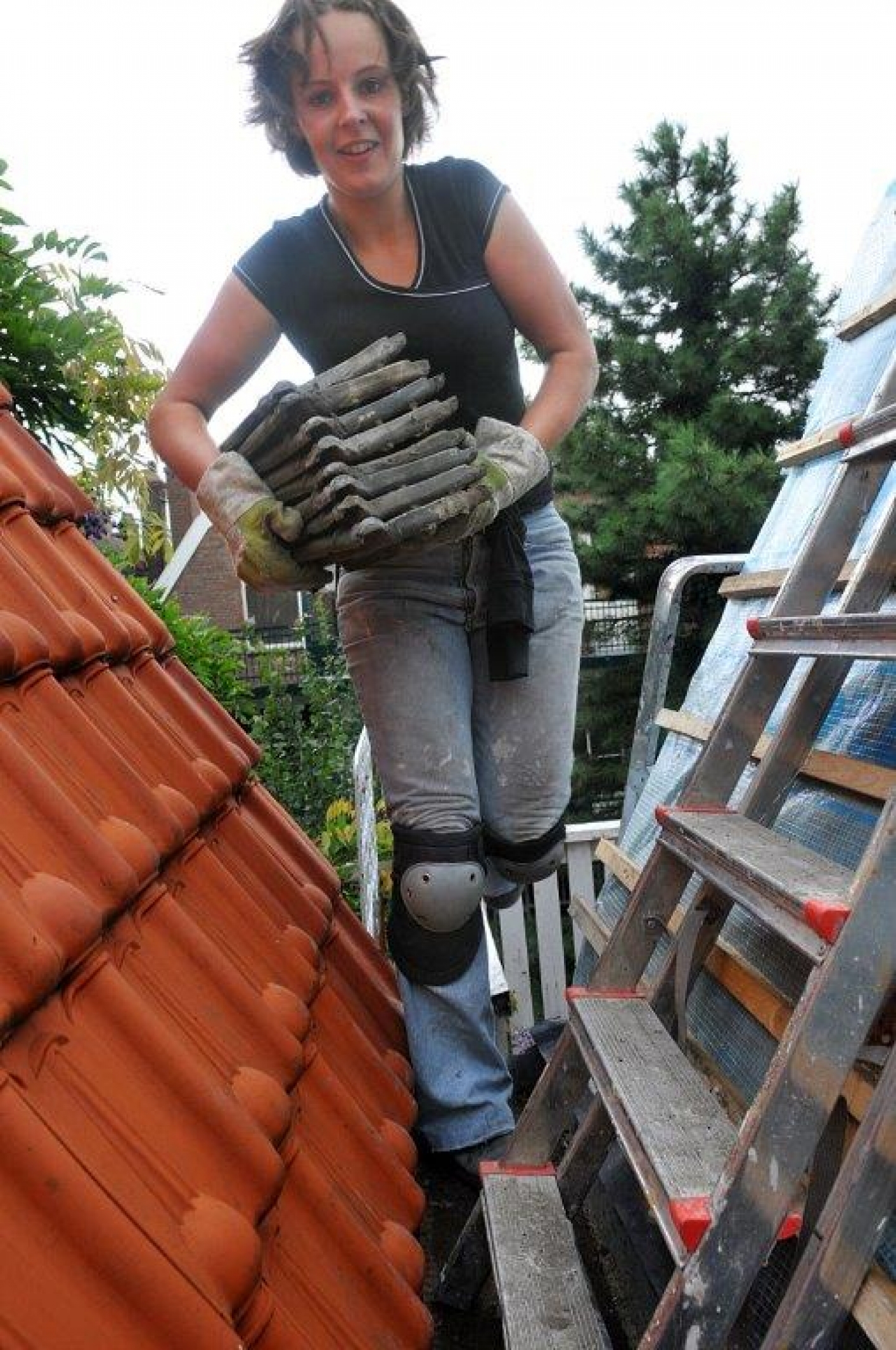 Vrouw is bezig met het leggen van dakpannen