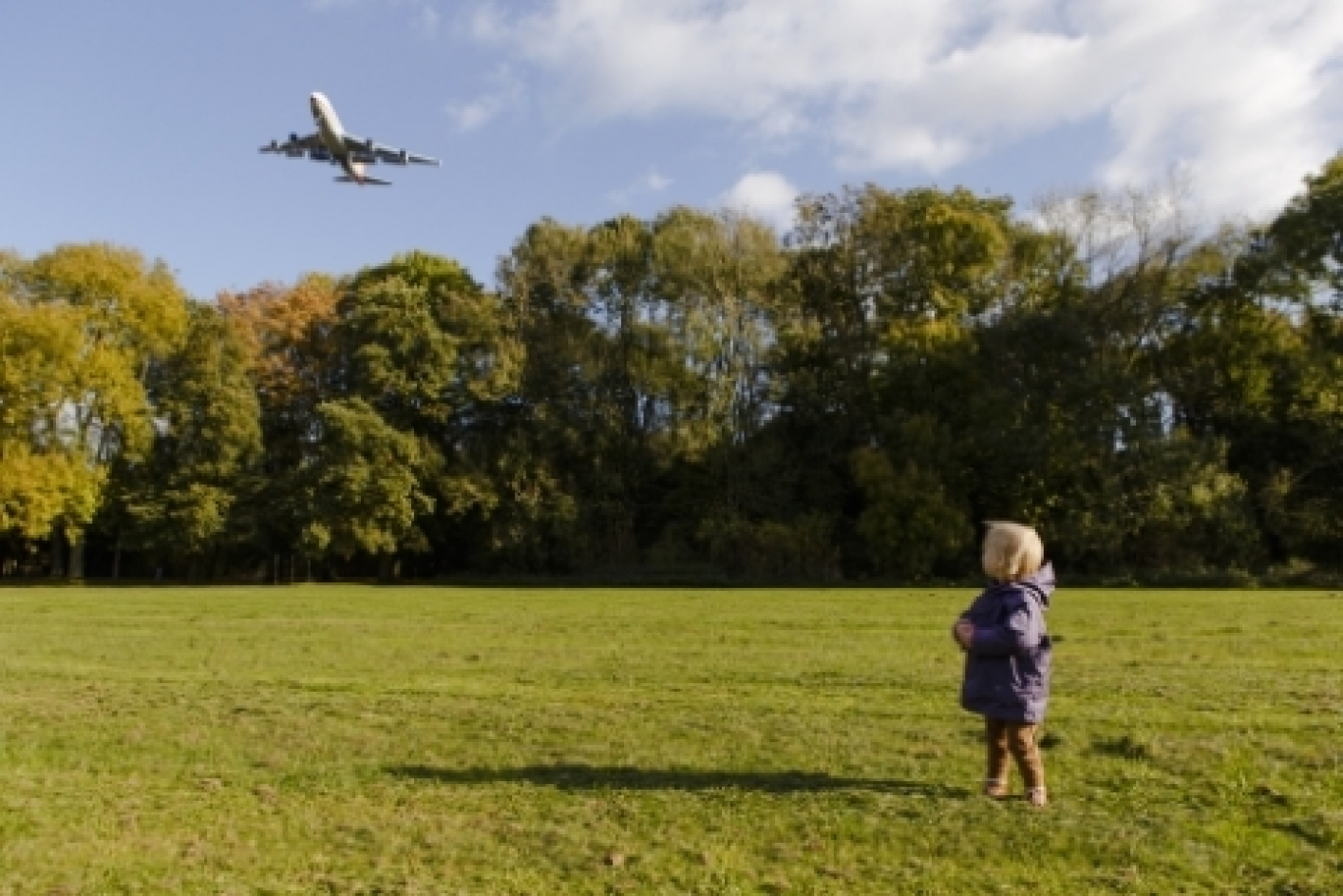 foto van kind in park met overvliegend vlieguig